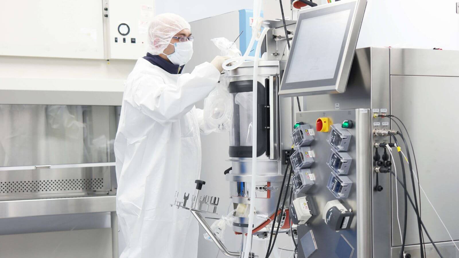 Pharmacist in protective clothing operating pharmaceutical lab machinery